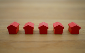 Image of five small red toy houses all lined up on a wooden table