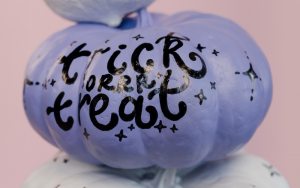 Purple painted pumpkin with the words "trick or treat" painted on in black paint for Halloween